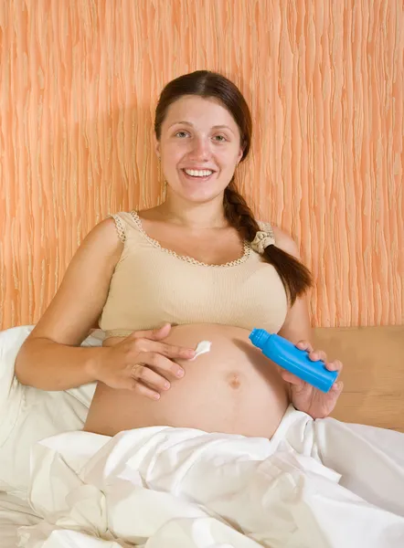 Беременная женщина наносит крем — стоковое фото