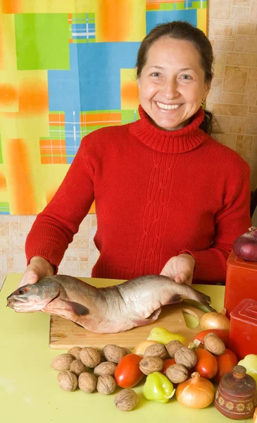 Ώριμη γυναίκα είναι το μαγείρεμα κόκκινη ψάρια — Φωτογραφία Αρχείου