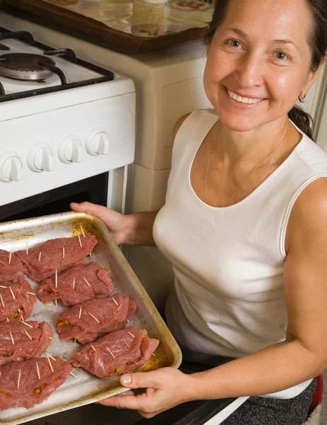 Woman putting stuffed beef into oven — Stock Photo, Image