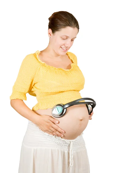 Беременная женщина в наушниках — стоковое фото