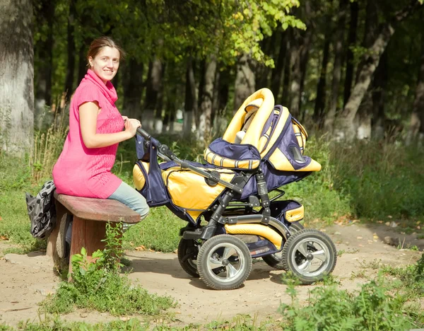 Kvinna med barnvagn i park — Stockfoto