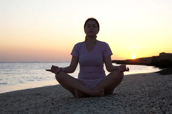 Девушка практикует йогу против восхода солнца — стоковое фото
