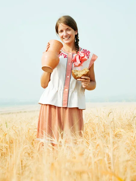 Meisje met brood en kruik op veld — Stockfoto