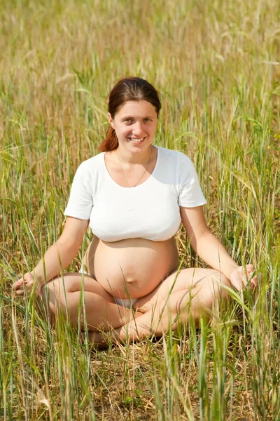 Pregnant woman doing yoga in cereal field — Stock Photo, Image