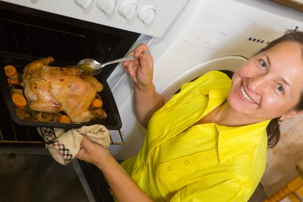Женщина готовит курицу в духовке — стоковое фото