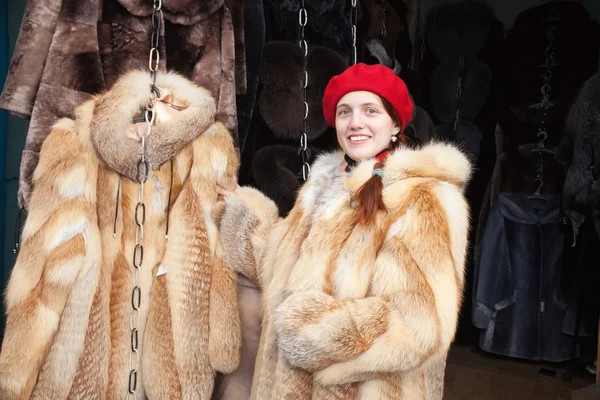 Girl chooses a fur coat — Stock Photo, Image