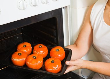 Cook putting farci tomato into oven clipart