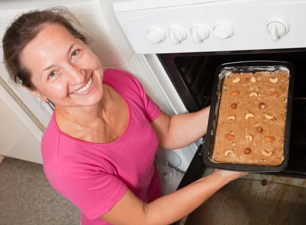 Женщина кладет тесто в духовку — стоковое фото