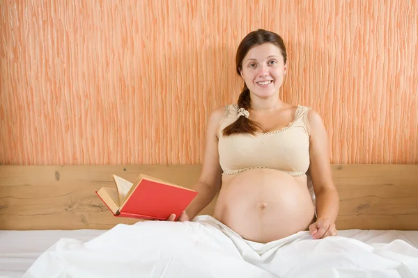 幸せな妊娠中の女性読書A本に家 — ストック写真