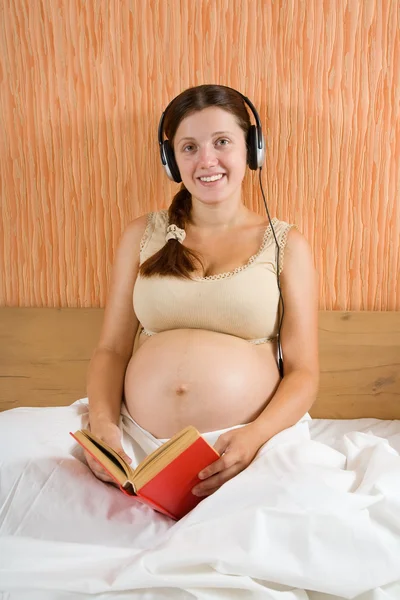 Ευτυχισμένη Έγκυος Γυναίκα Διαβάζοντας Και Ακούγοντας Μουσική Στο Σπίτι — Φωτογραφία Αρχείου