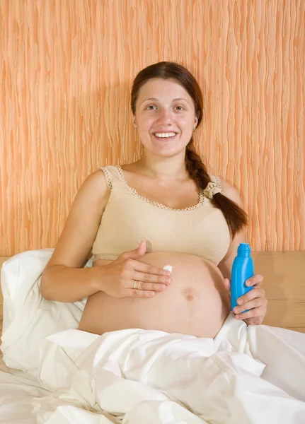 Беременная женщина с кремом для тела — стоковое фото