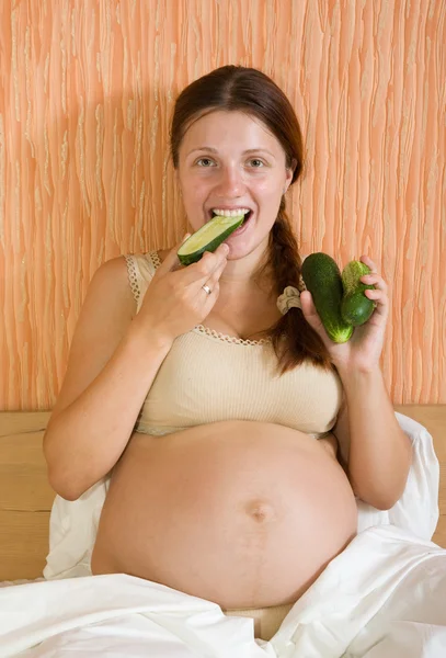 Těhotná žena jíst okurky — Stock fotografie