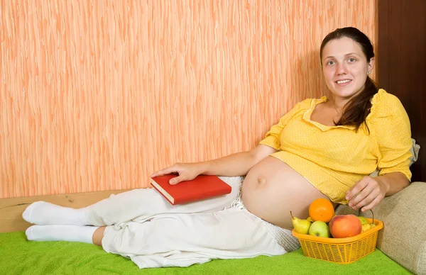Kobieta Ciąży Leżąc Kanapie Salonie Książki Owoce — Zdjęcie stockowe