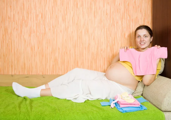 Femme enceinte avec des vêtements de bébé — Photo