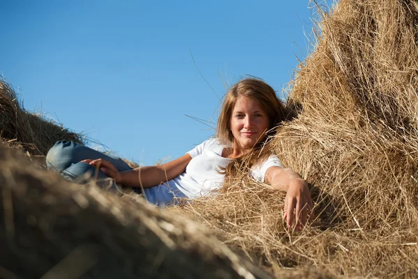新鮮なわら俵で休んできれいな女の子 — ストック写真