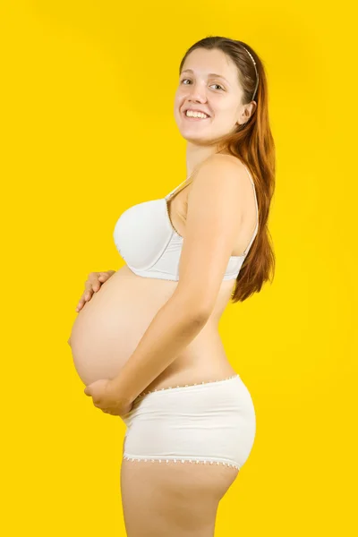 Mutlu hamile bir kadın tutarak karın — Stok fotoğraf