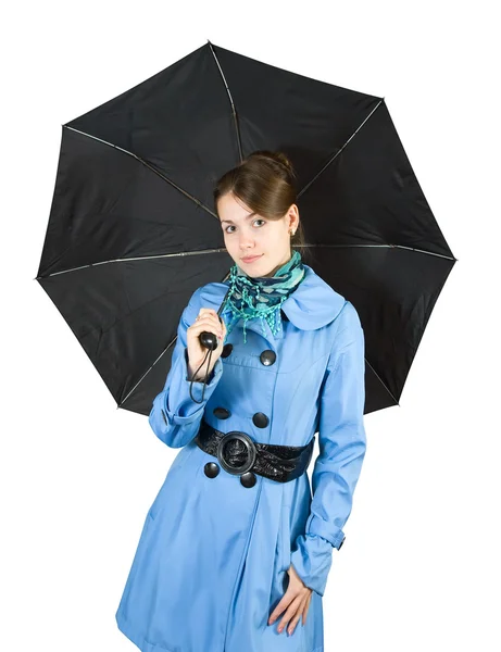 美しい若い女性は白い背景で隔離の黒い傘を保持している青いコートを着ています — ストック写真