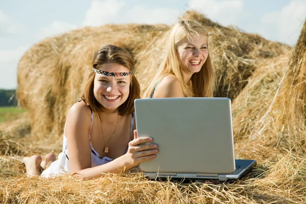 Girls with notebook laying on hay — Stock Photo, Image