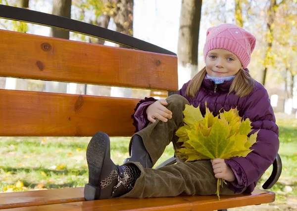 坐在秋天公园长凳上的小女孩 — 图库照片