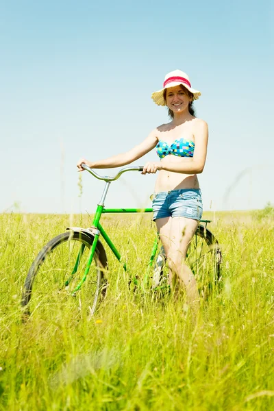 美丽的女孩骑自行车在草田 — 图库照片