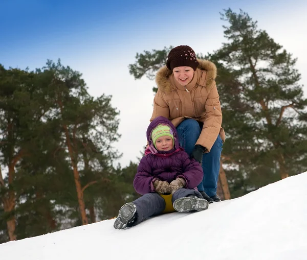 Mor Med Litet Barn Glidande Snön Mot Vinter Park — Stockfoto