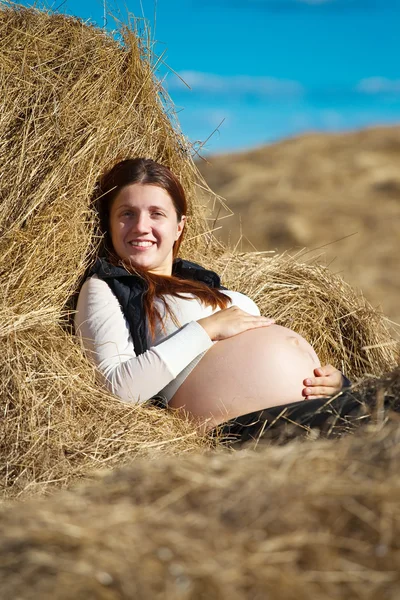 Pregnant woman on hay Stock Image