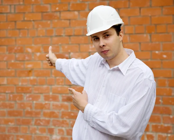 Costruttore che punta al muro di mattoni — Foto Stock