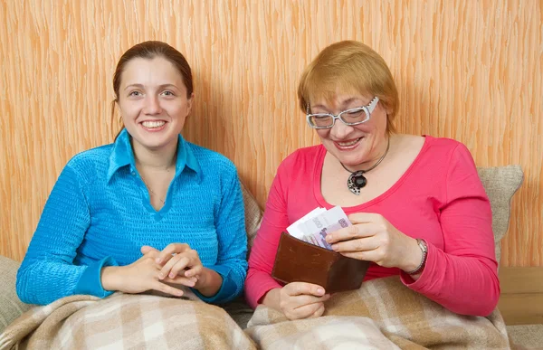 快乐的女人把钱交给她成年女儿在家里的沙发上 — 图库照片