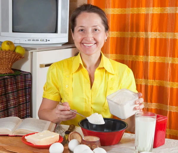 Kobieta wylewa mąki do patelni — Zdjęcie stockowe