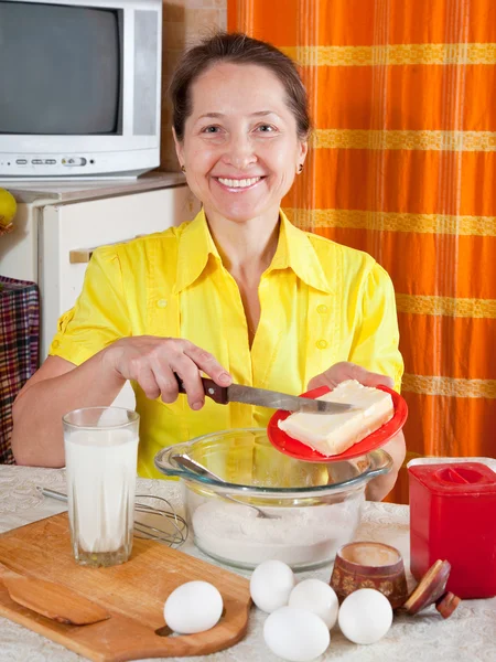 Woman adds margarine into dough — Stock Photo, Image