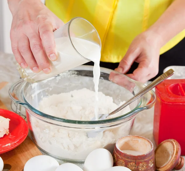 Cook hands pouring milk into flour — Stock Photo, Image