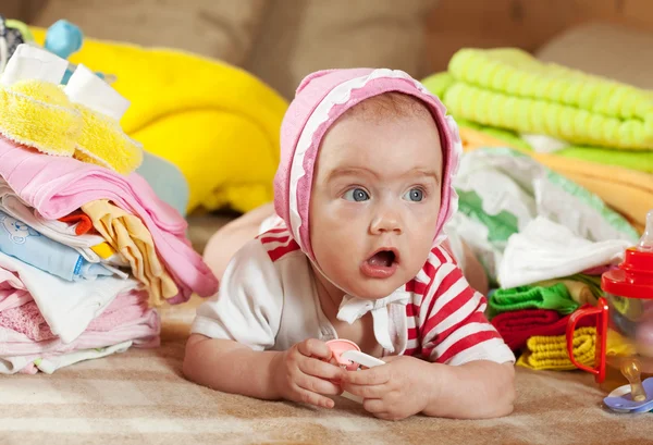Bébé fille avec tas de vêtements de bébé — Photo