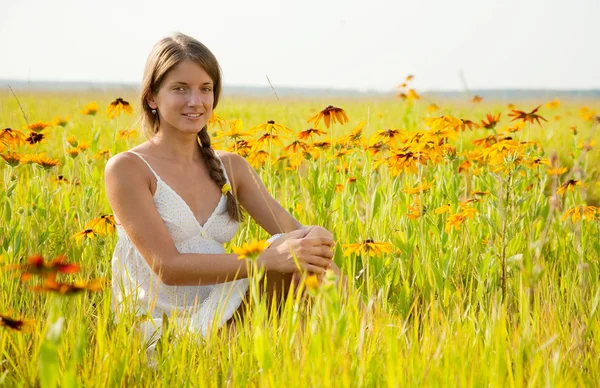 여자는 꽃 초원에 앉아 — 스톡 사진