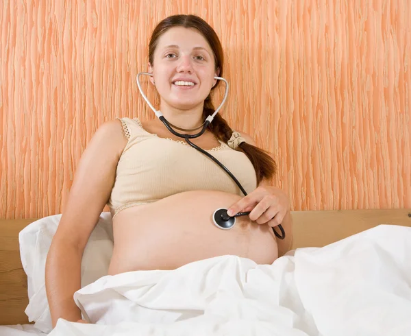 Mujer embarazada escucha su vientre — Foto de Stock