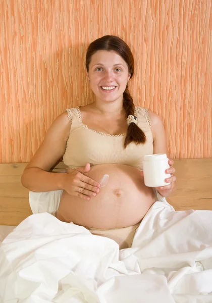 Mulher grávida aplicando creme — Fotografia de Stock