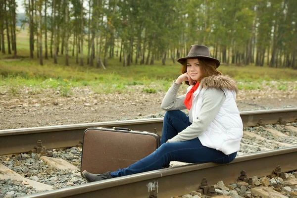 Девушка сидит с чемоданом — стоковое фото