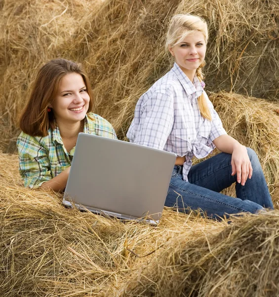 Girls resting with laptop on hay — Stock Photo, Image