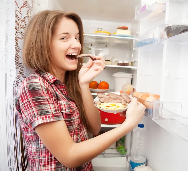 Dívka jíst maso z ledničky — Stock fotografie