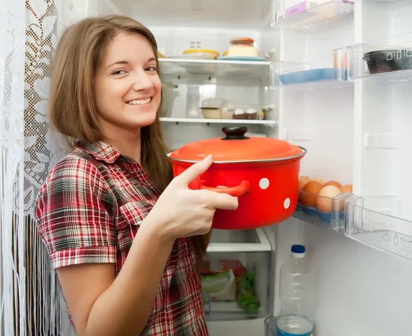 Девушка кладет кастрюлю в холодильник — стоковое фото