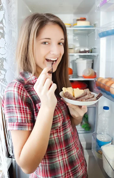 Девушка ест мясо из холодильника — стоковое фото