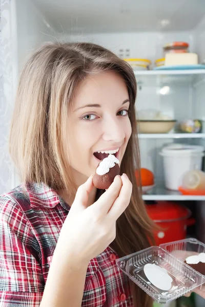 Girl eating pastry from fridge — Stock Photo, Image