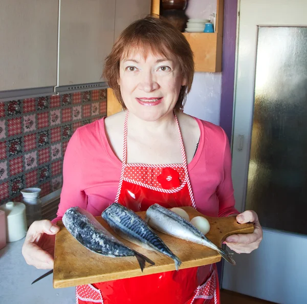 Woman with mackerel in kitchen — Zdjęcie stockowe