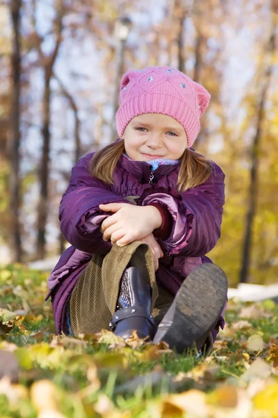 Chica sentada en hojas de otoño — Foto de Stock
