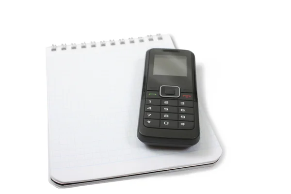 En tom anteckningsbok med en svart telefon på toppen — Stockfoto