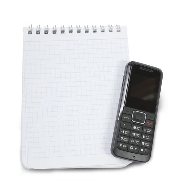 En tom anteckningsbok med en svart telefon på toppen — Stockfoto