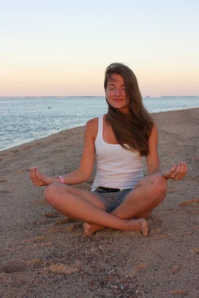 Mladá žena cvičí jógu na pláži — Stock fotografie