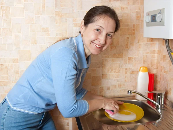Nainen pesee astiat keittiössä — kuvapankkivalokuva