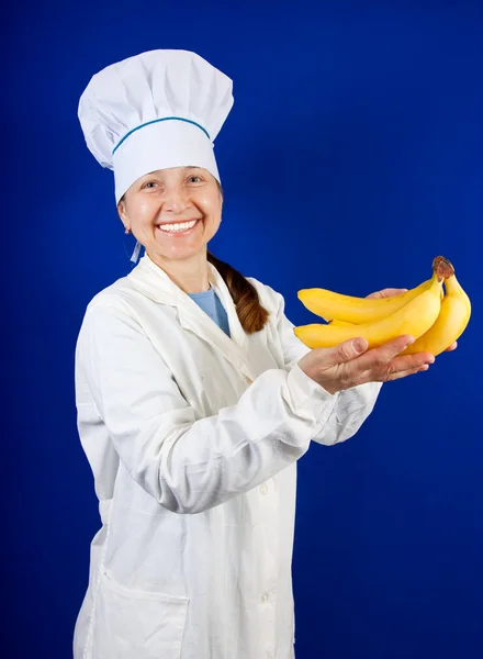 Female cook holding bananas — Stock Photo, Image