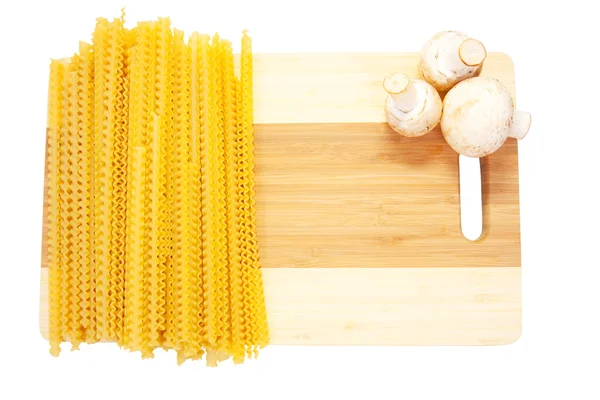 Espaguete amarelo na placa de corte — Fotografia de Stock