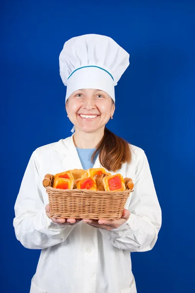 Female cook with cookie over blue — Stock Photo, Image